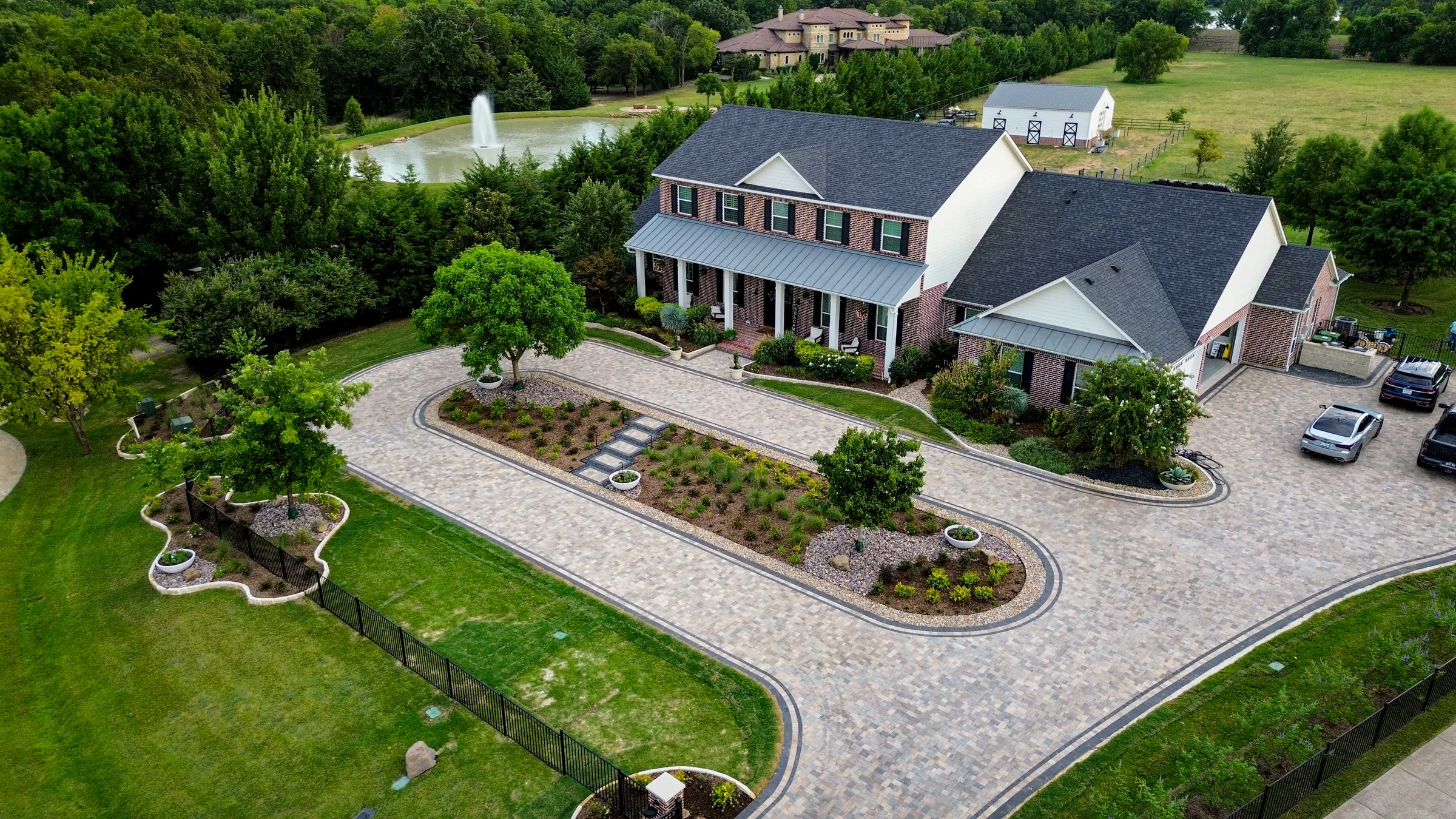 Aerial view of a looped paver driveway surrounding a long landscaped island