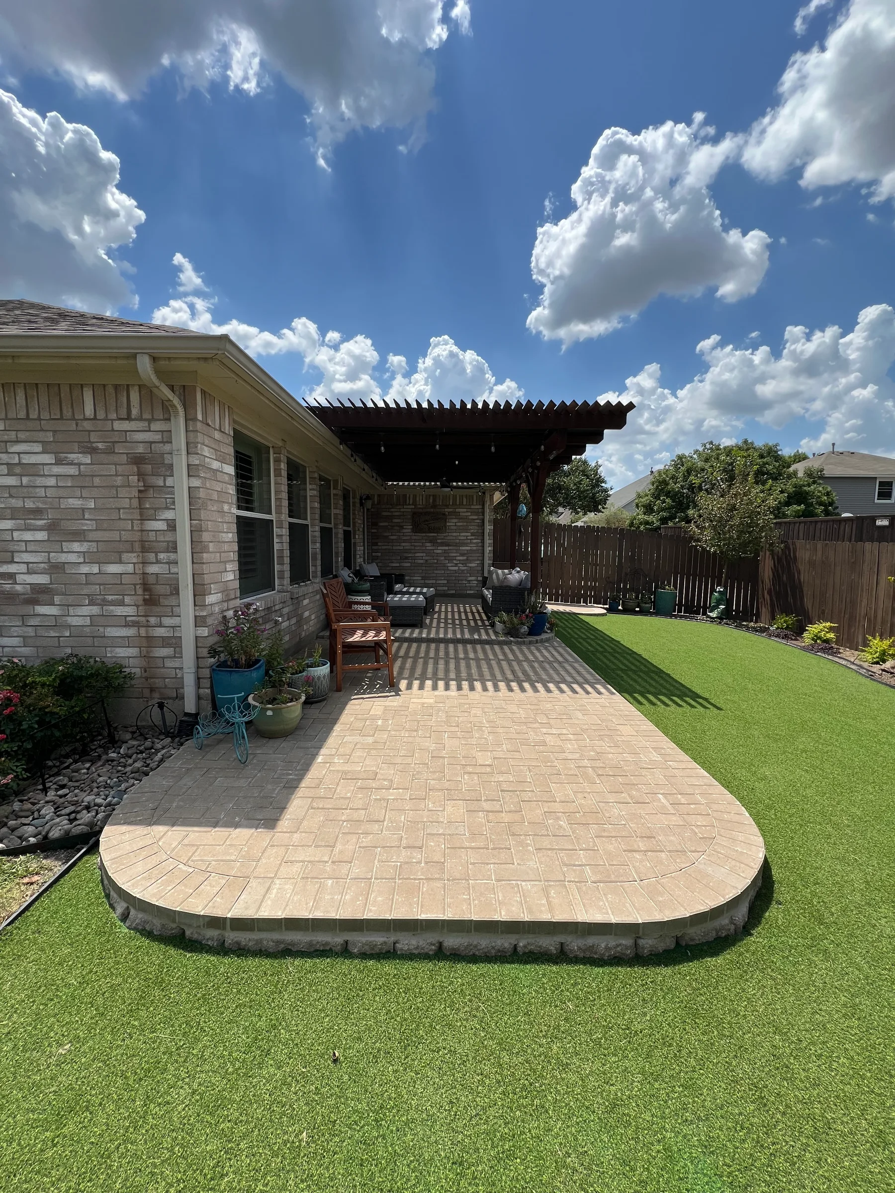 Backyard with paver patio, artificial turf, and a covered outdoor living area