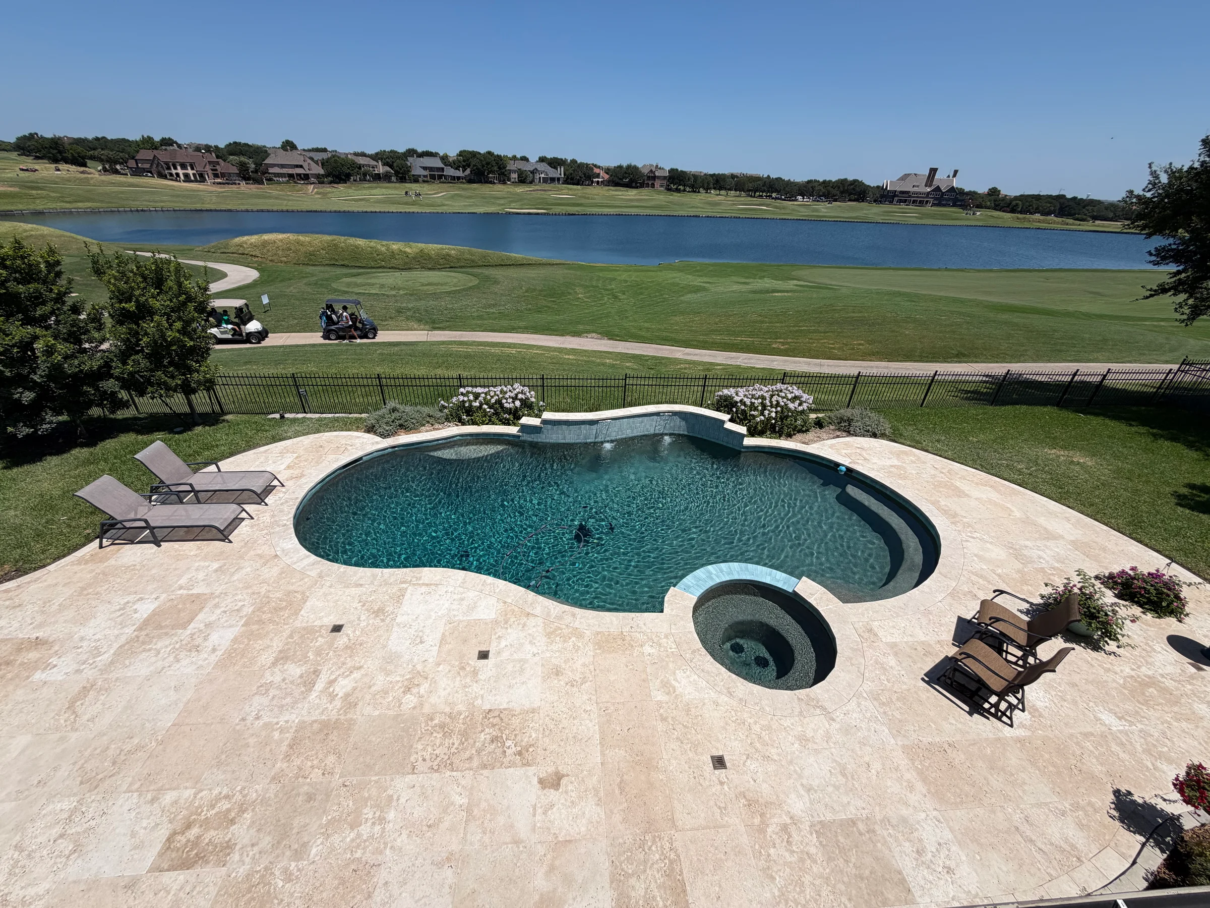 Lakefront swimming pool, spa, and light-toned pool deck by Precision Pavers