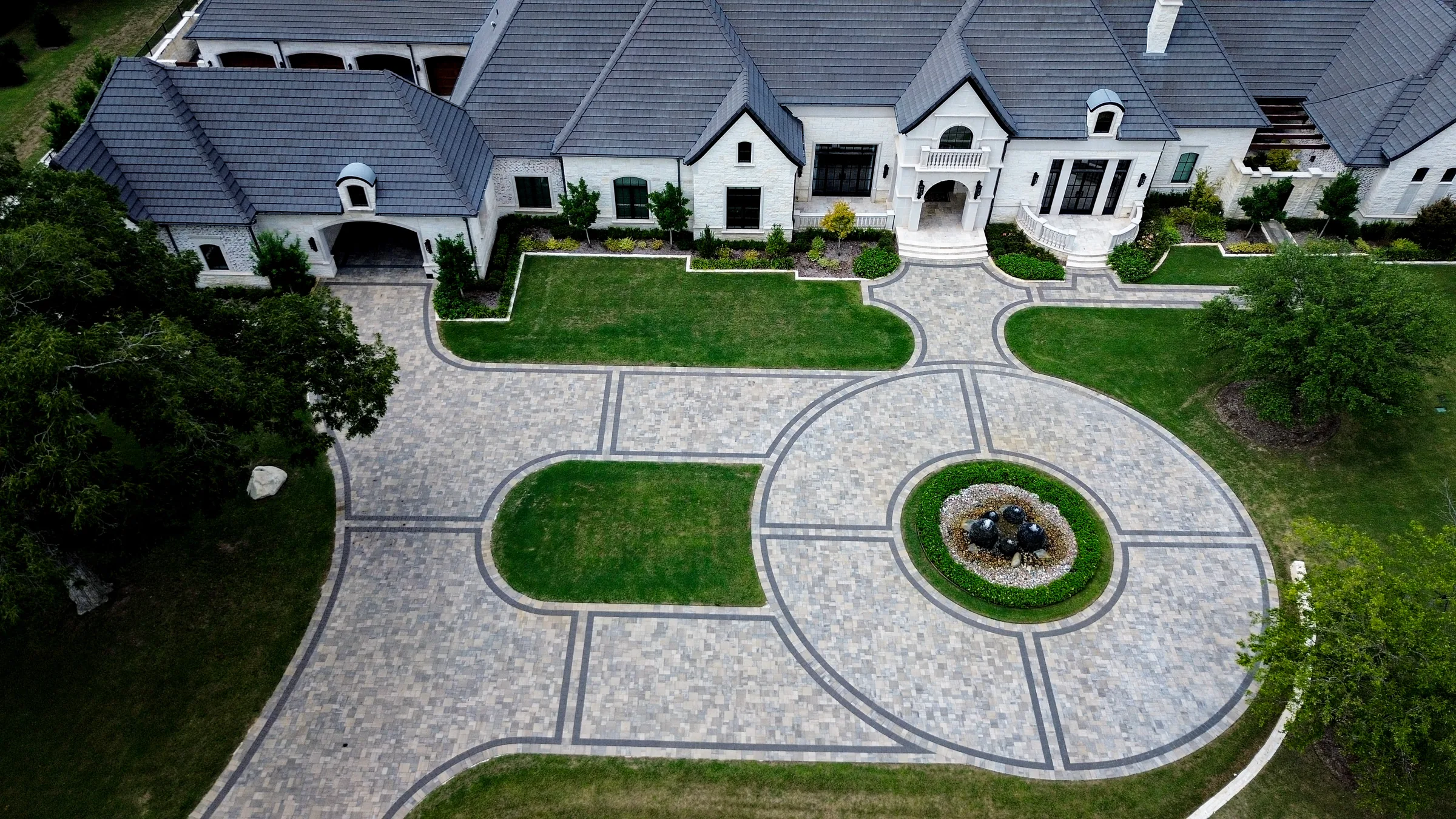 Overhead view of an expansive paver driveway divided by curved dark border lines