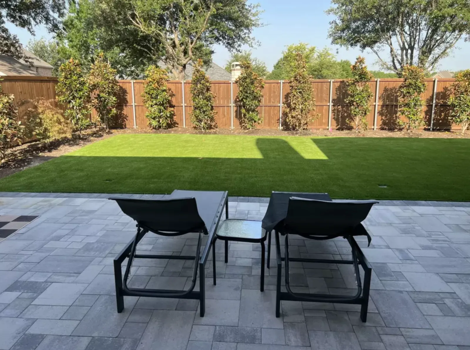 Paver patio overlooking a rectangular artificial turf lawn
