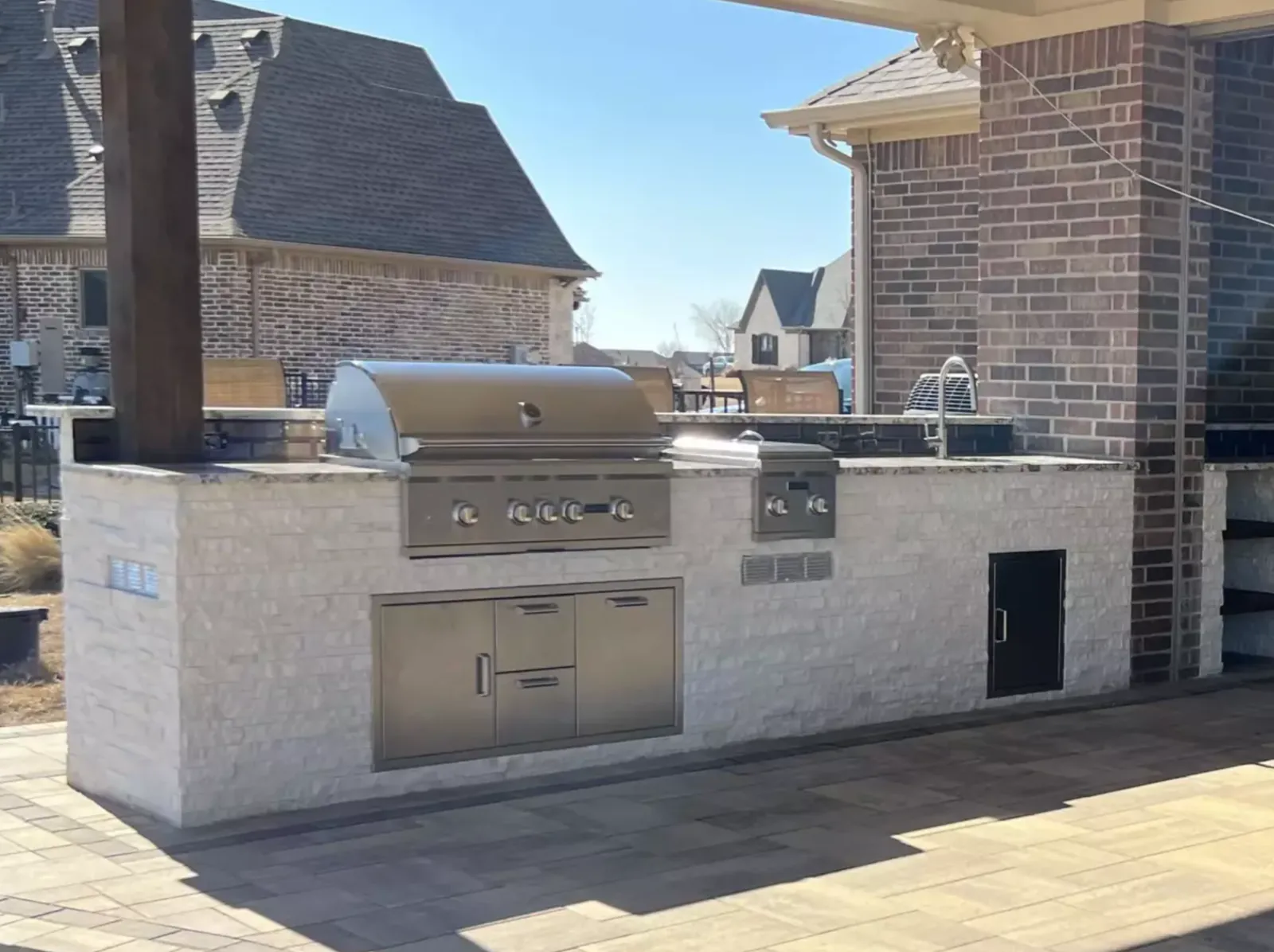 Built-in outdoor grill and storage set into a light stone kitchen island