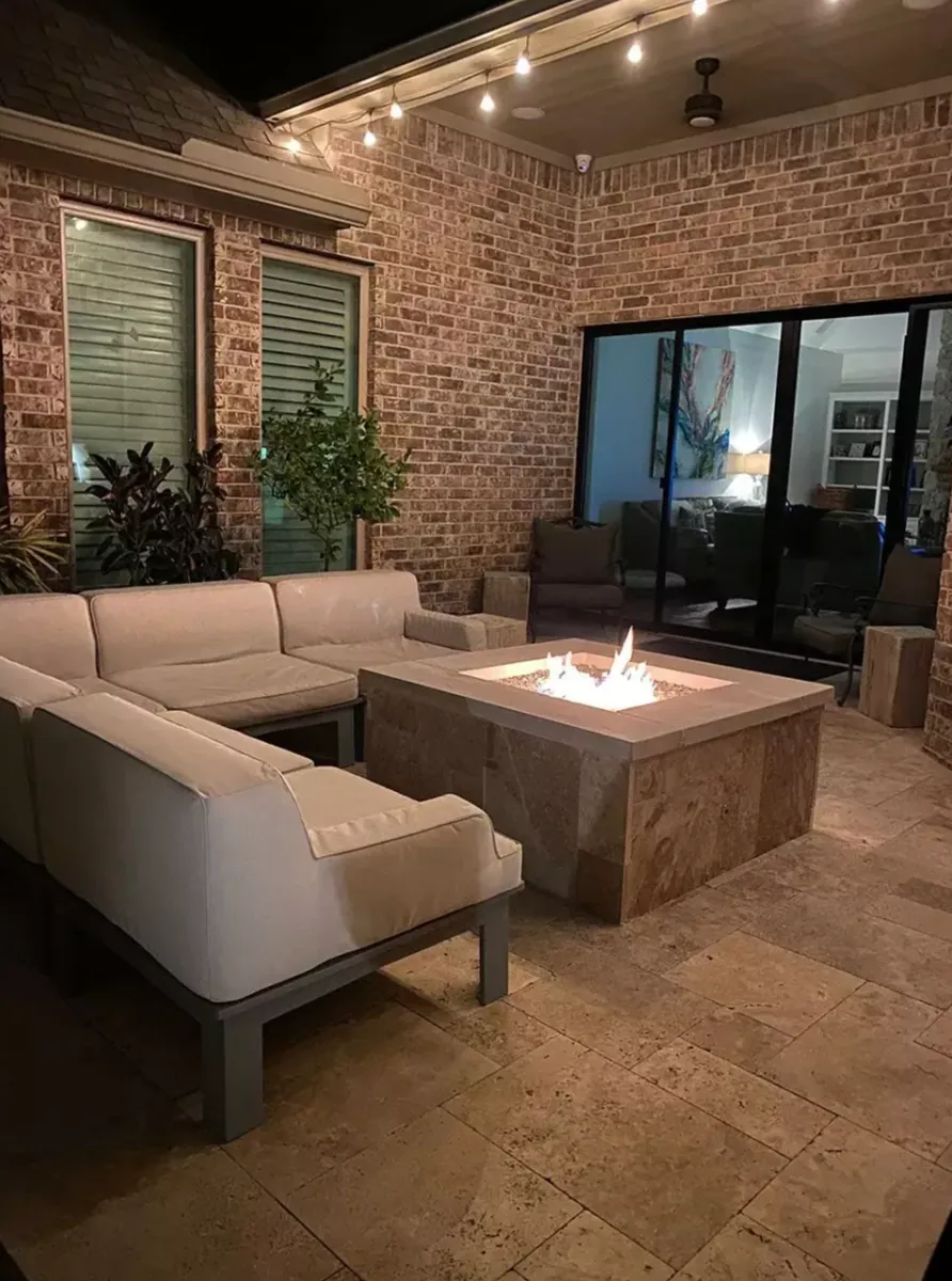 Covered brick patio furnished around a square gas fire table