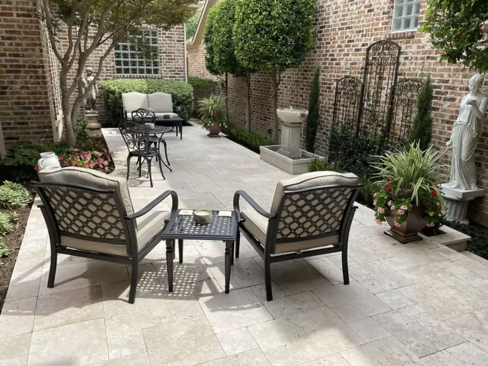 Intimate enclosed courtyard with a light stone patio and outdoor seating