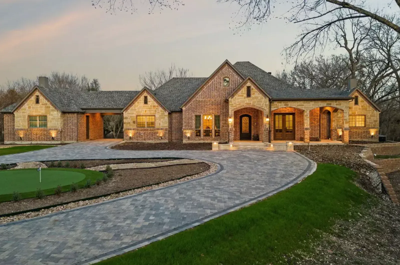 Estate arrival with an expansive paver drive and integrated putting green