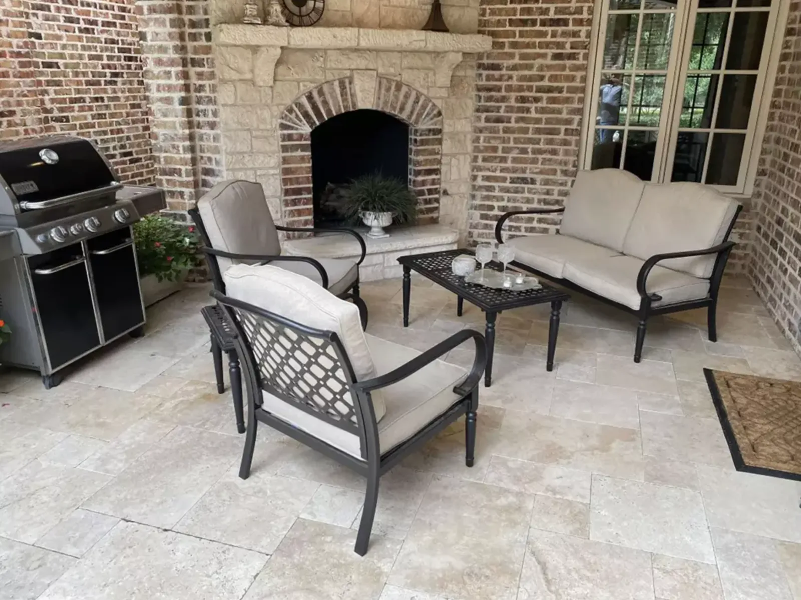 Covered courtyard seating arranged in front of an outdoor masonry fireplace