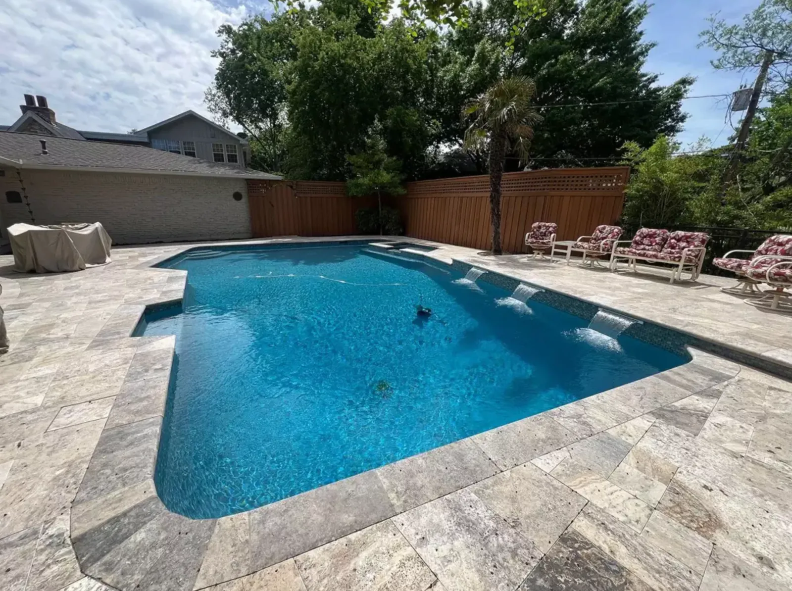 Light stone deck surrounding a modern swimming pool