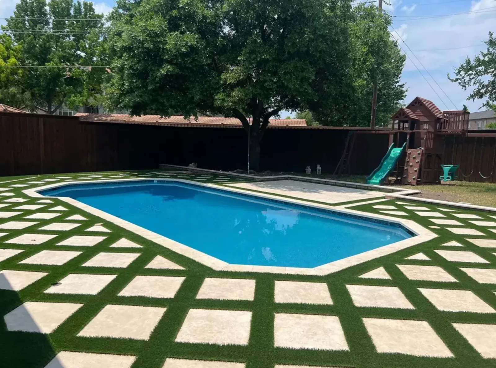 Rectangular pool surrounded by large stone slabs set in a geometric turf grid
