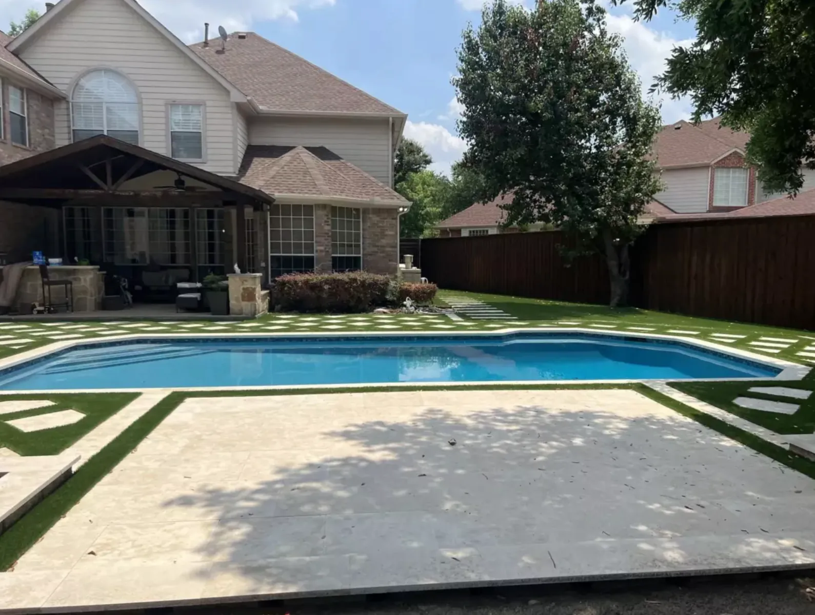 Pool deck with large light slabs and narrow artificial turf inlays