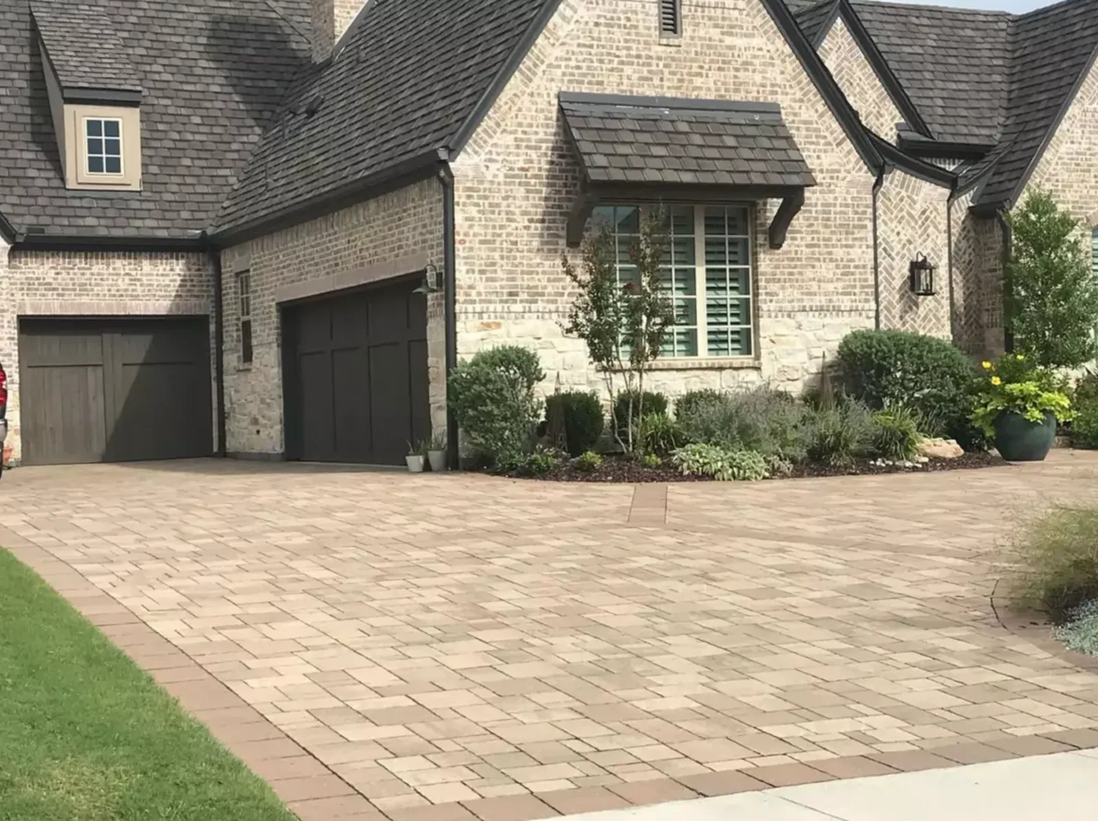 Warm-toned paver driveway complementing a light brick home