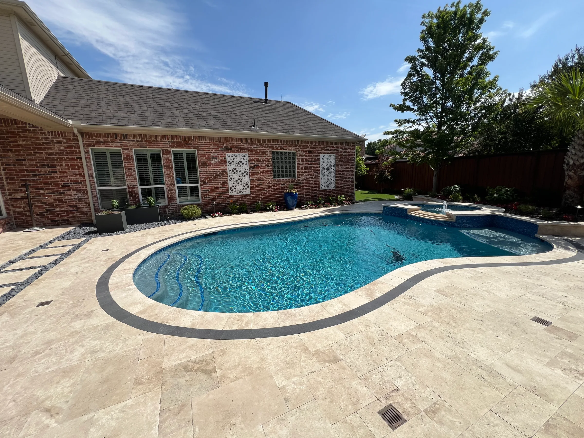 Completed residential swimming pool and surrounding stone pool deck/patio