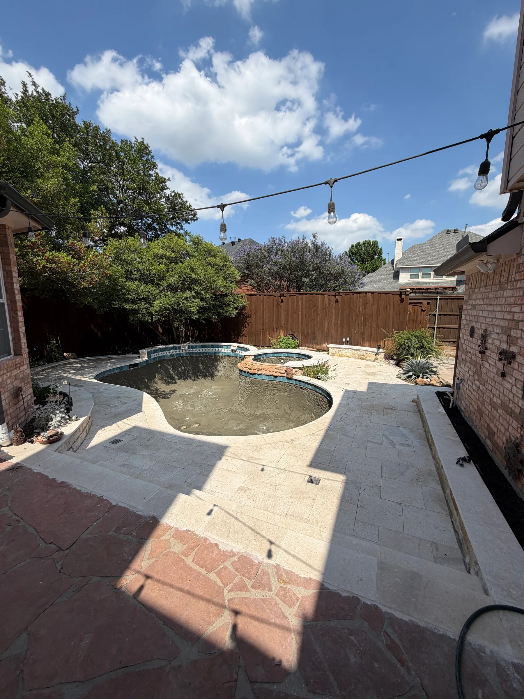 Residential backyard pool and surrounding stone patio/deck